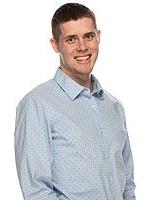 Nathan Follett stands in front of a white background, he smiles toward the camera.